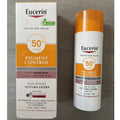 Eucerin Pigment Control Sun Fluid 50+ SPF 50 sunscreen bottle and its retail box, displayed side-by-side on a gray textured background.